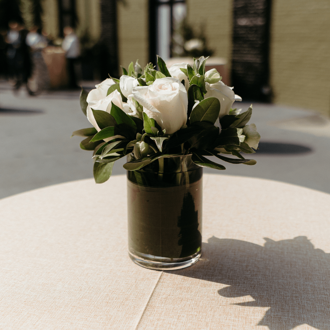 Simple white and green floral arrangement featuring white Roses and greenery for a cocktail table
