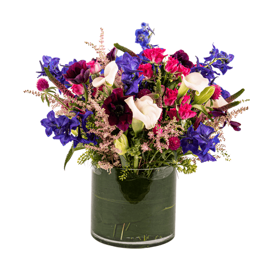 Floral arrangement featuring blue Delphinium, Purple Anemones and white Calla Lilies.