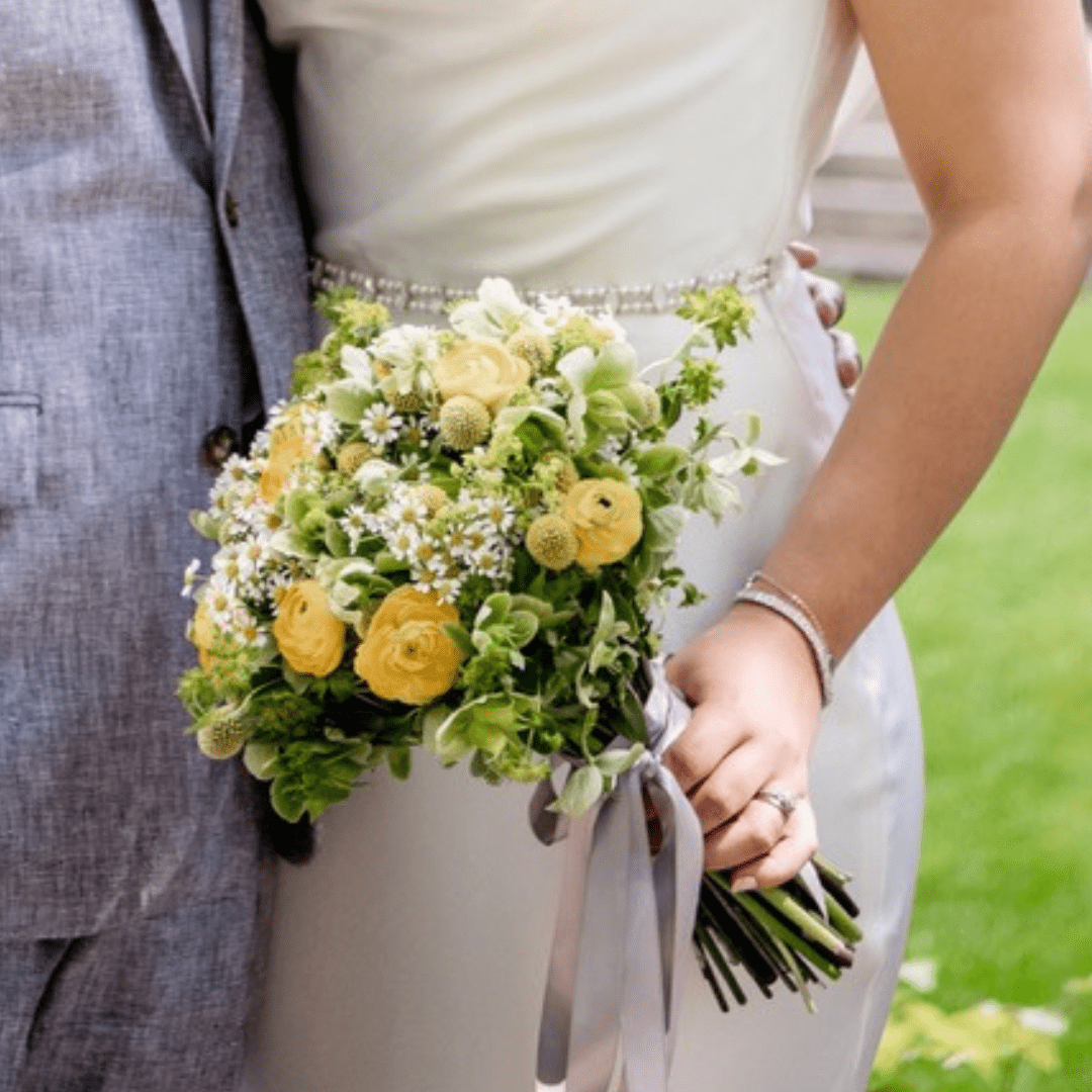 Small bridal bouquet featuring yellow, green and white flowers including Ranunculus and Chamomile